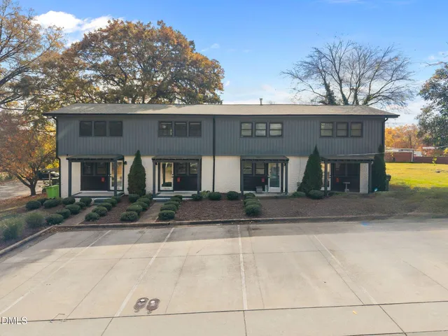 a view of a white house with large tree next to a yard