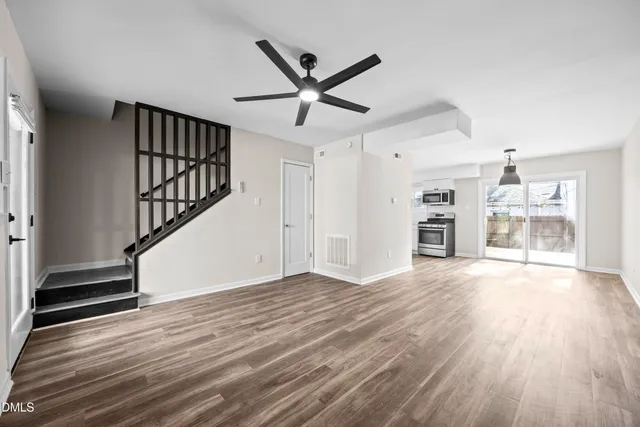 a view of empty room with wooden floor and fan