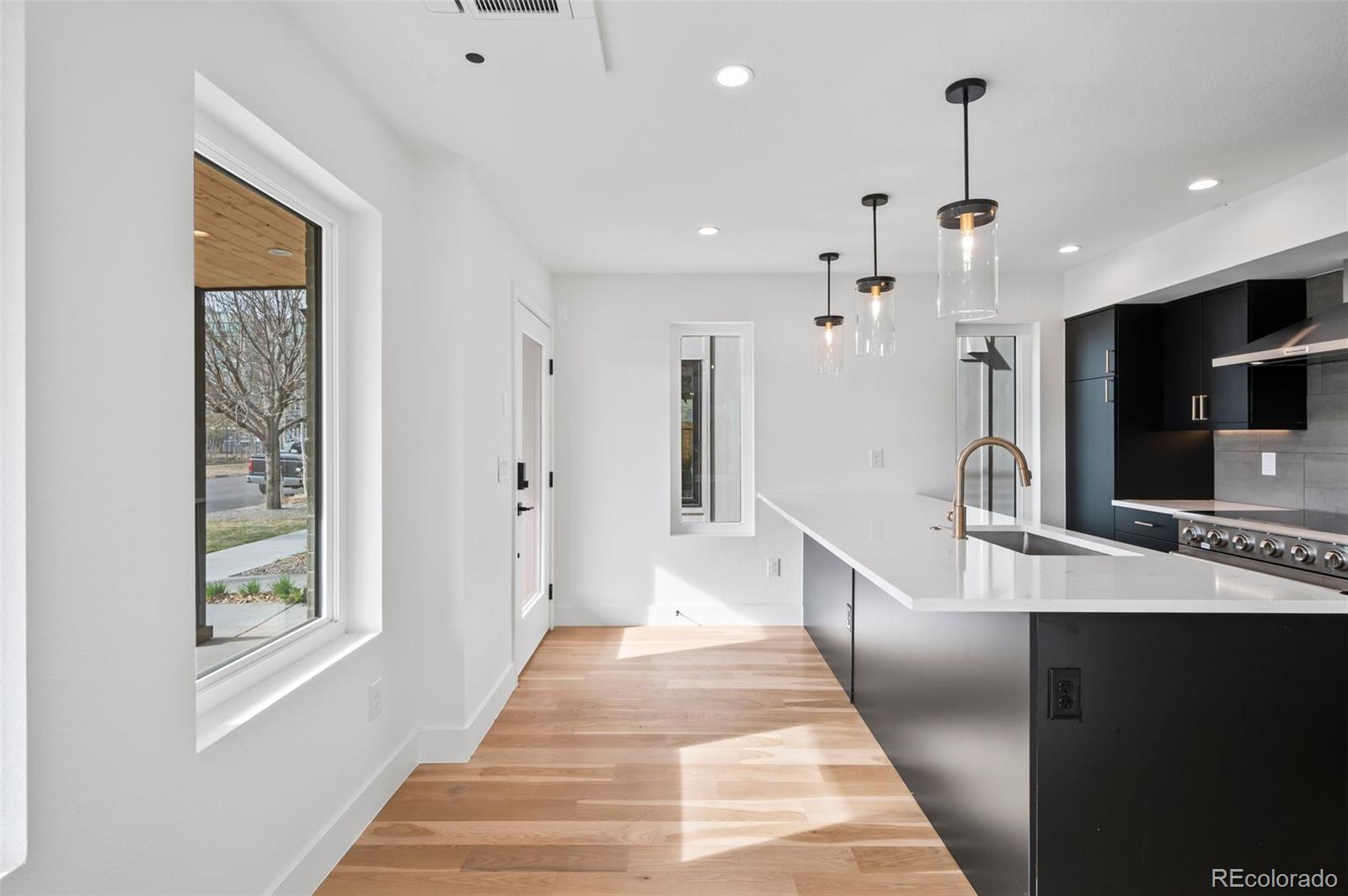 2451 Lawrence Street Denver, CO 80205 - Photo 10 of 48 a view of a kitchen with kitchen island granite countertop a refrigerator a oven a sink and blue cabinets
