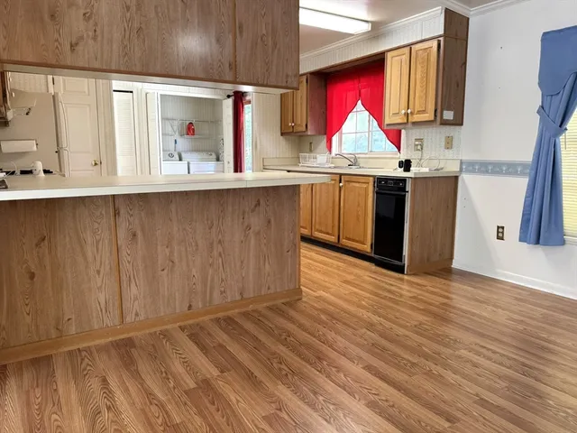 a kitchen with kitchen island granite countertop wooden floors and wide window
