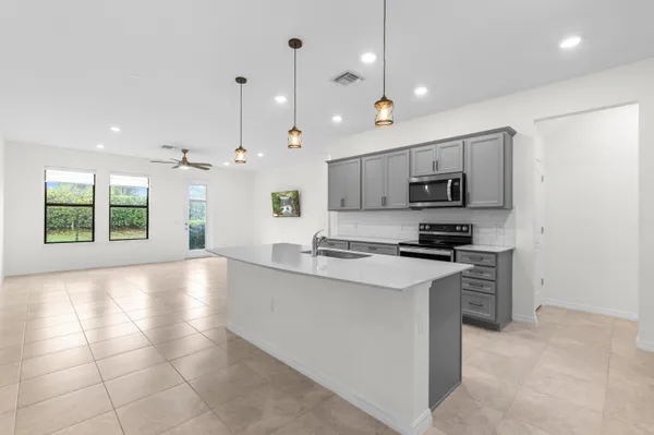 a large kitchen with stainless steel appliances granite countertop a stove a sink a refrigerator and a counter top space