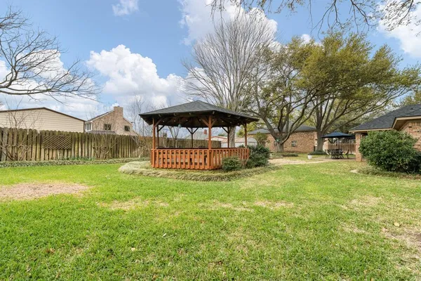 a view of a park that has a large trees with wooden fence