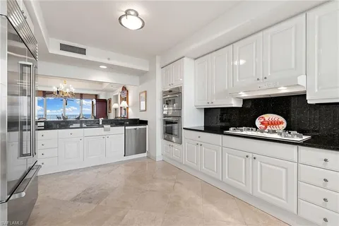 a kitchen with granite countertop white cabinets and stainless steel appliances