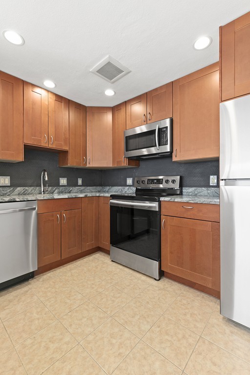 a kitchen with stainless steel appliances granite countertop a stove a sink dishwasher a refrigerator and a microwave