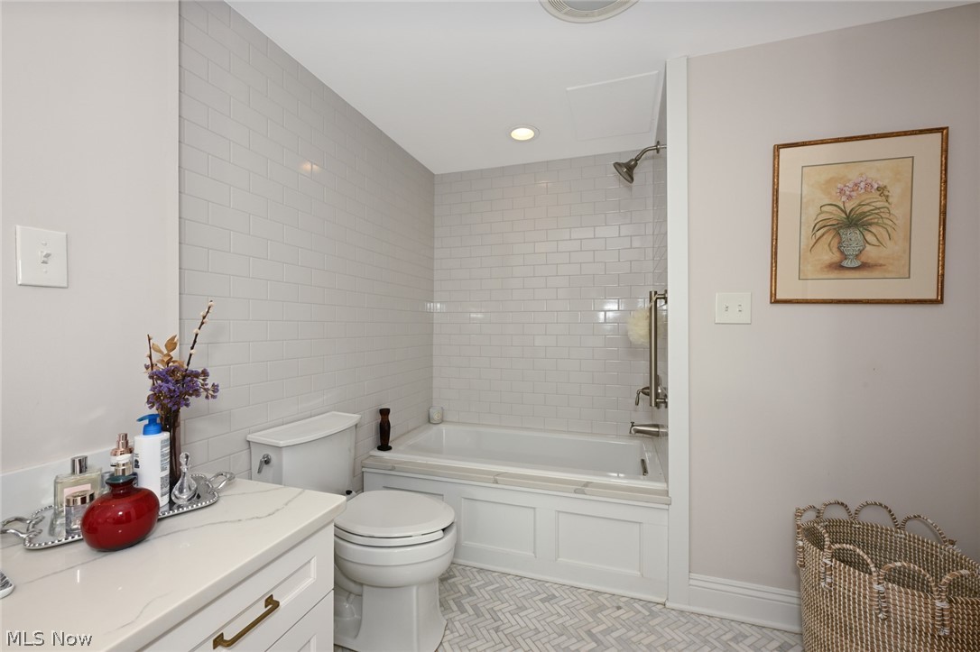 275 North Portage Path, Unit 3B Akron, OH 44303 - Photo 12 of 16 Bathroom featuring a bathtub with subway tile surround, a toilet, a vanity with a white countertop, and herringbone pattern floor tiles
