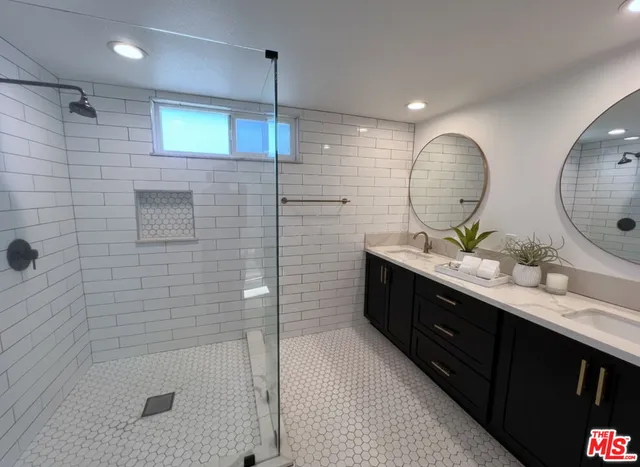 a bathroom with a double vanity sink mirror and shower