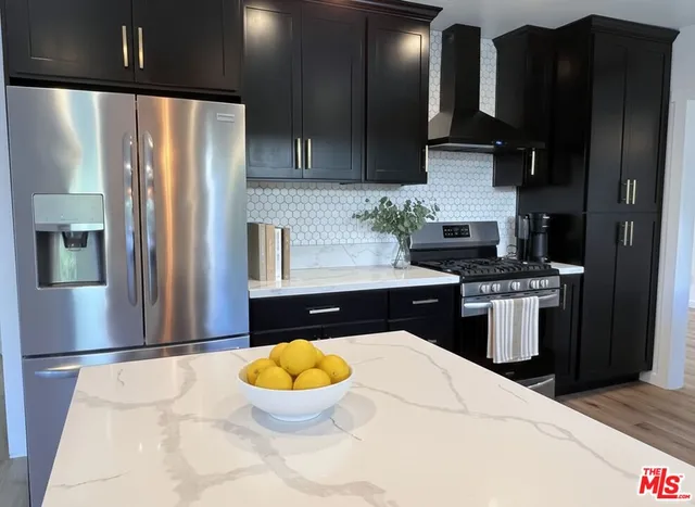 a kitchen with stainless steel appliances granite countertop a refrigerator a stove and a sink