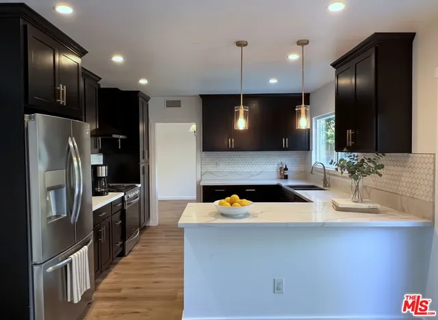 a kitchen with stainless steel appliances a sink a stove a refrigerator and microwave