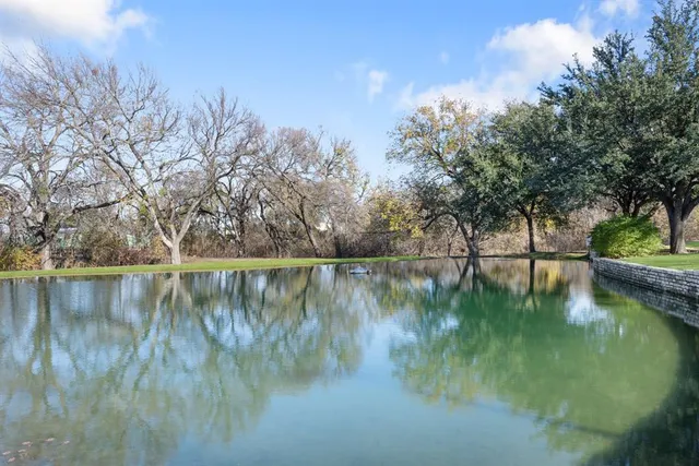 a view of a lake with a yard and large trees