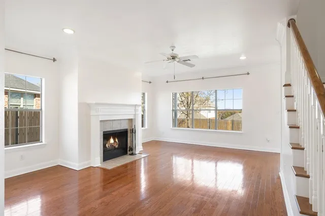 a view of an empty room with wooden floor fireplace and a window