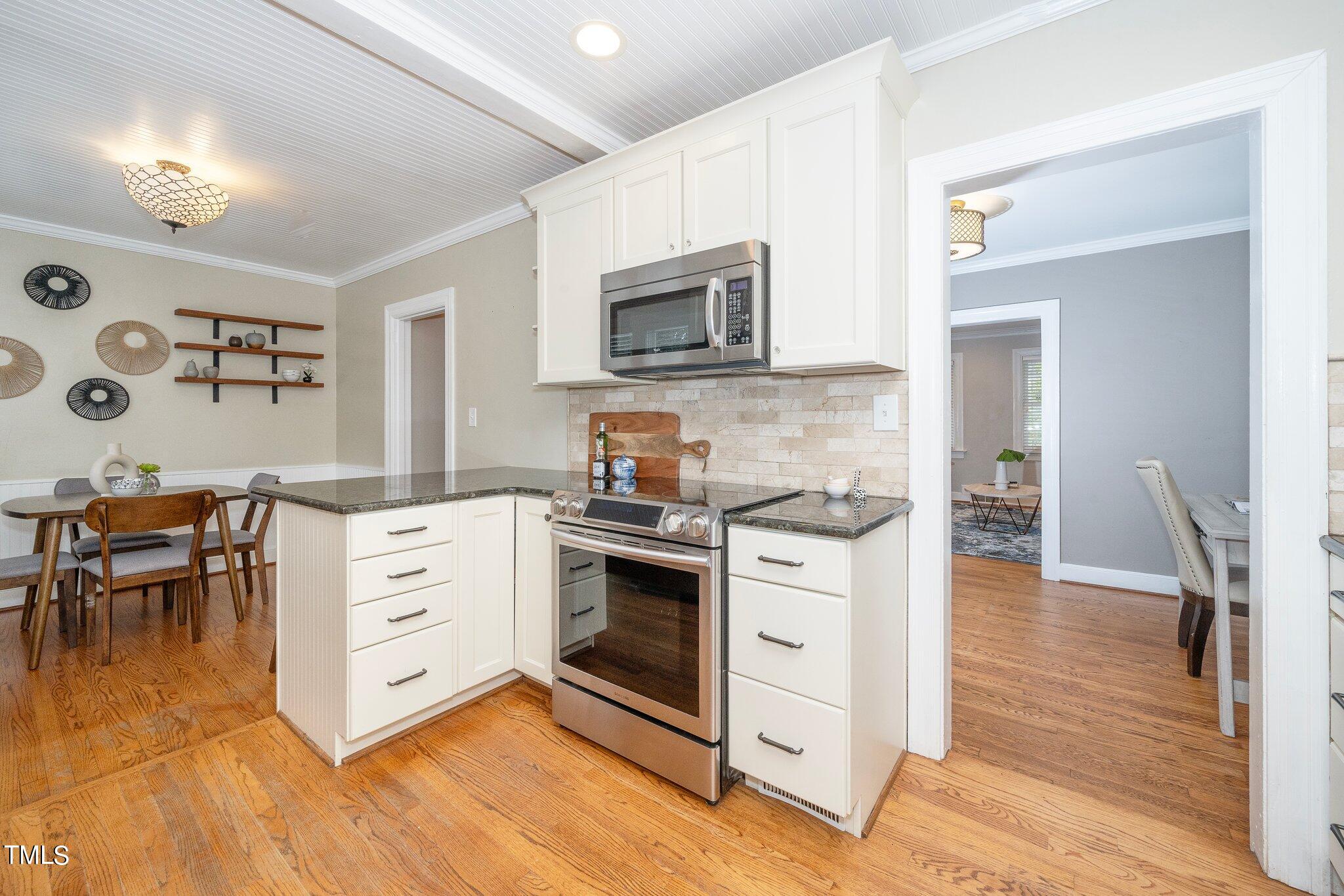 406 Brooks Avenue Raleigh, NC 27607 - Photo 12 of 33 a kitchen with stainless steel appliances white cabinets a stove a sink and a microwave
