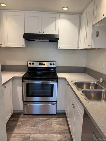 a kitchen with granite countertop white cabinets and stainless steel appliances
