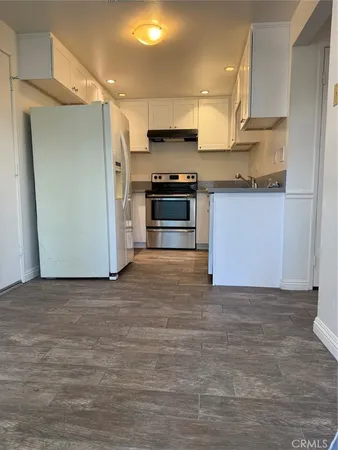 a kitchen with granite countertop a refrigerator and a stove top oven