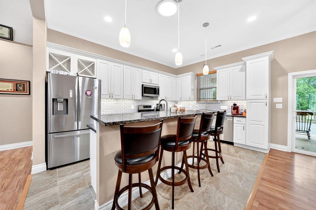 5230 Esquire Estates Road Mabank, TX 75156 - Photo 11 of 39 Spacious kitchen featuring white cabinetry, stone countertops, stainless steel appliances, tile flooring, and a subway tile backsplash