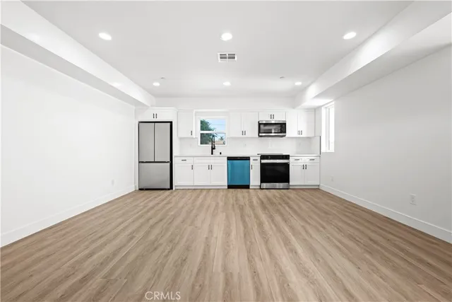 a view of kitchen with stainless steel appliances wooden floor and large window