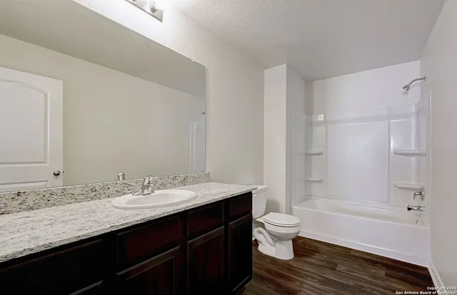 a bathroom with a granite countertop sink a toilet a shower and a mirror