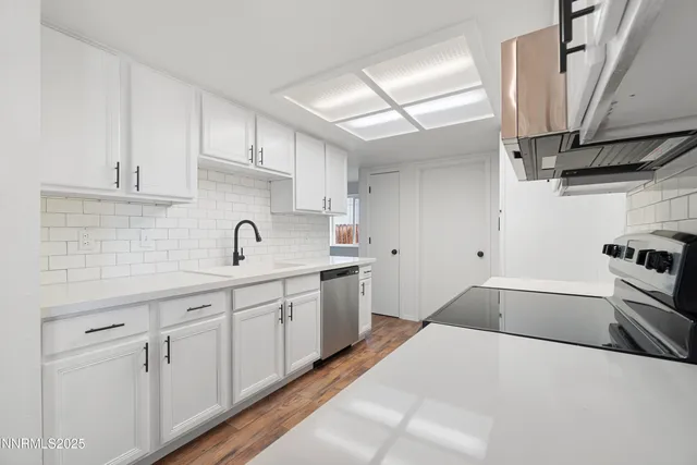 a kitchen with granite countertop a sink stainless steel appliances and cabinets