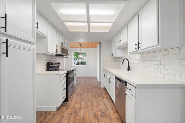 a kitchen with stainless steel appliances granite countertop a sink a stove and a refrigerator