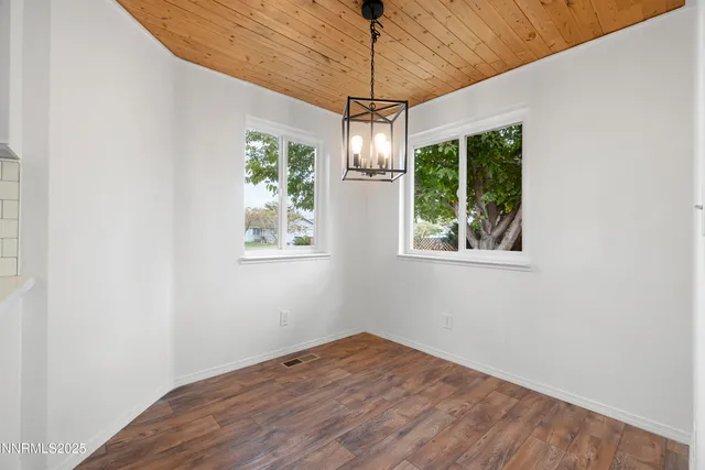 a view of empty room with wooden floor and windows