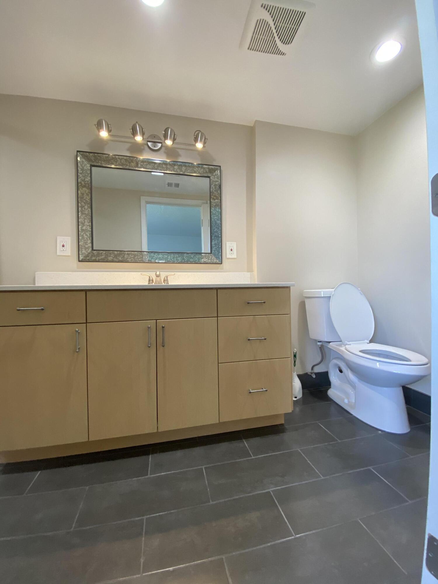 9355 Southwest 8th Street, Unit 305 Boca Raton, FL 33428 - Photo 2 of 13 a bathroom with a toilet sink and mirror