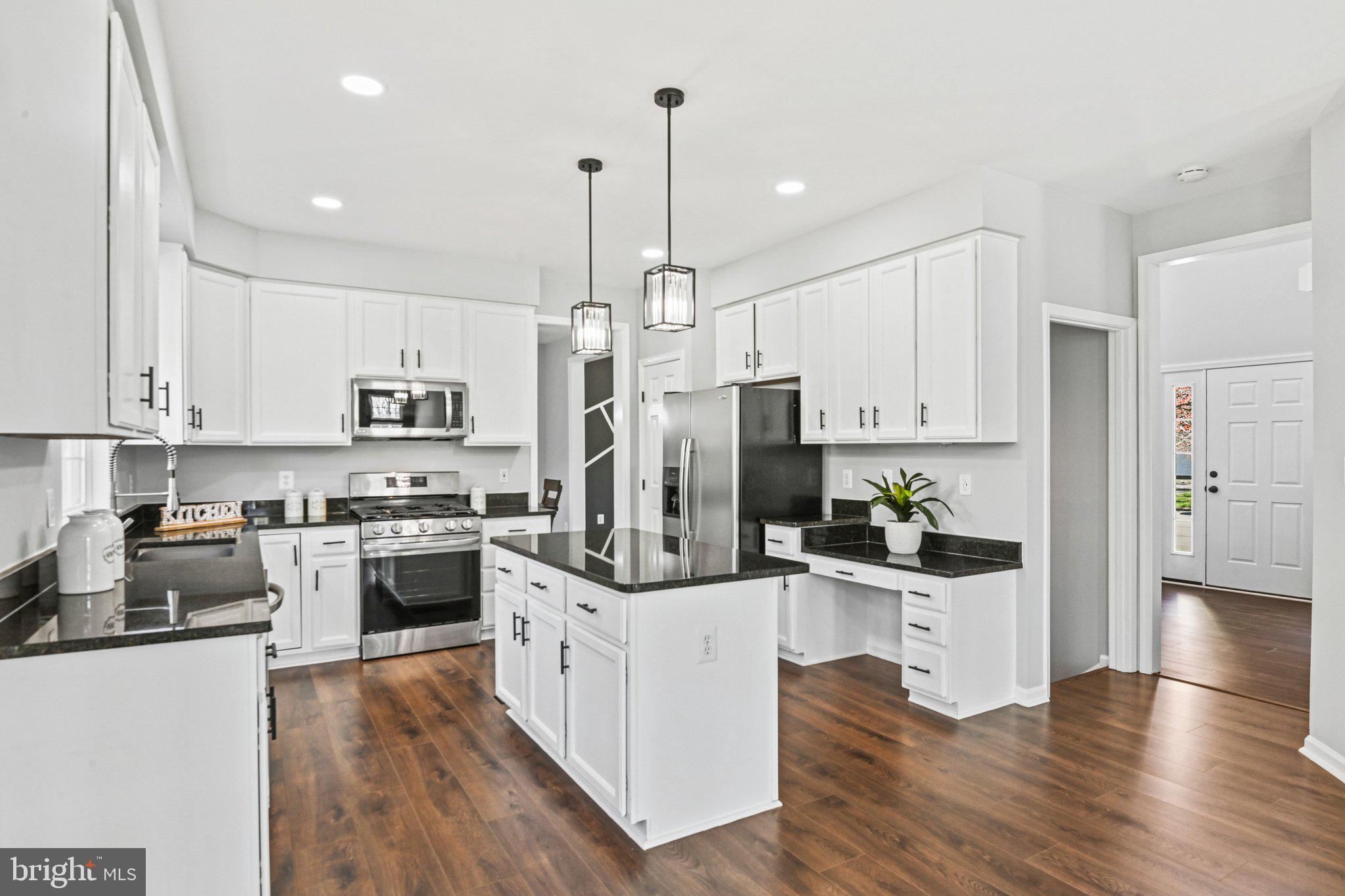 20733 Rainsboro Drive Ashburn, VA 20147 - Photo 13 of 63 a kitchen with stainless steel appliances kitchen island granite countertop a wooden floors and white cabinets