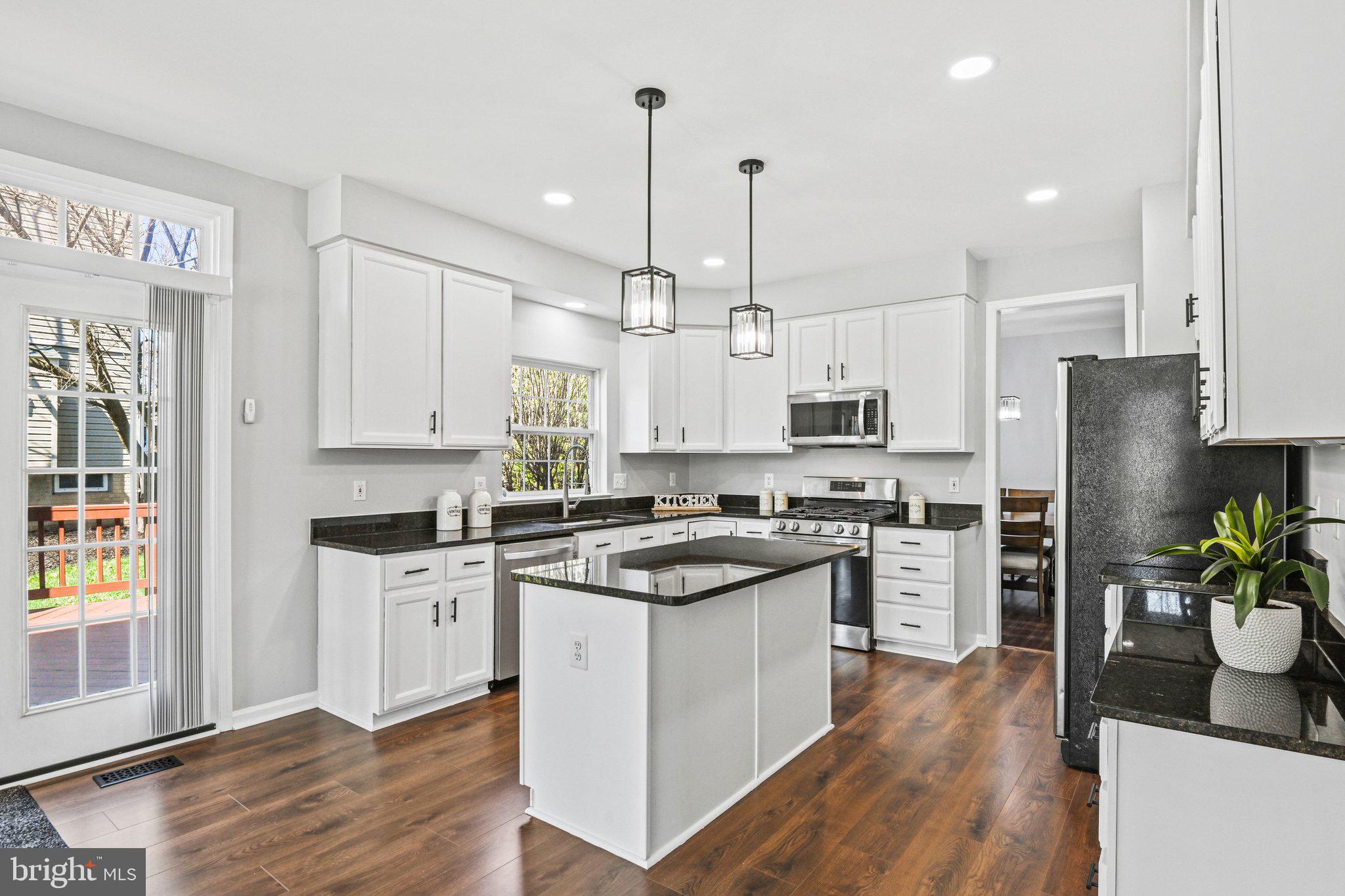 20733 Rainsboro Drive Ashburn, VA 20147 - Photo 16 of 63 a kitchen with stainless steel appliances a stove a sink dishwasher a refrigerator white cabinets and wooden floor
