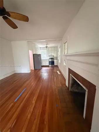 a view of a livingroom with wooden floor and a kitchen