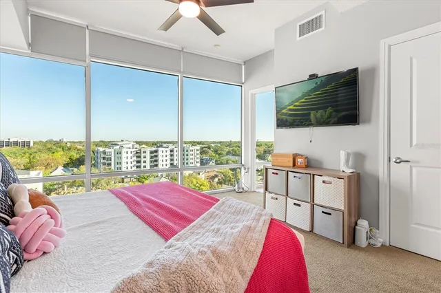 a living room with a bed furniture flat screen tv and a refrigerator