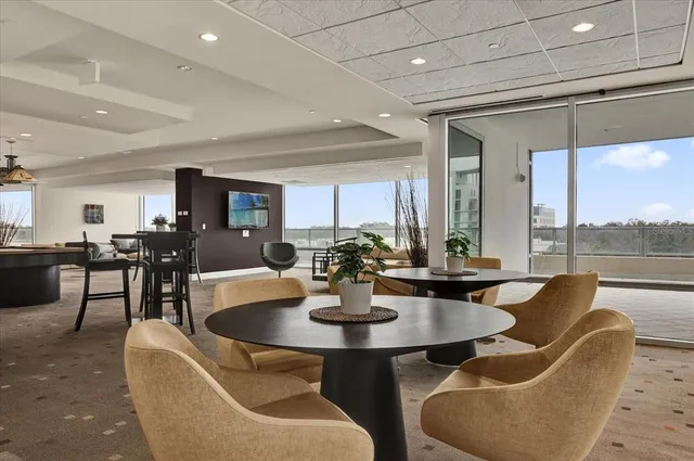 a dining room with couches a coffee table and chairs next to a large window