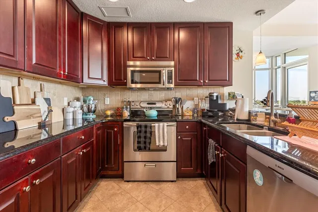a kitchen with stainless steel appliances granite countertop wooden cabinets a sink and a stove