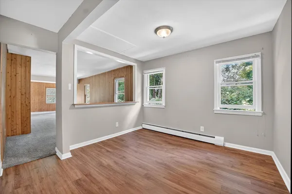 an empty room with wooden floor and windows