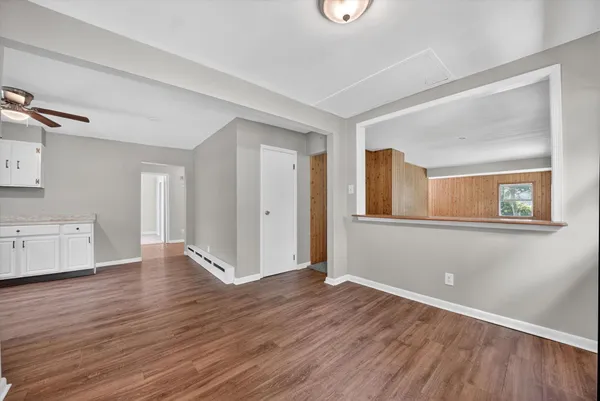 a view of an empty room with wooden floor and a window