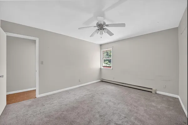 an empty room with windows and fan