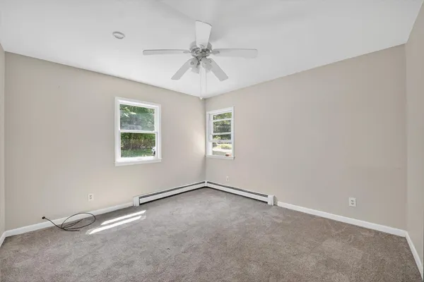 an empty room with windows and fan