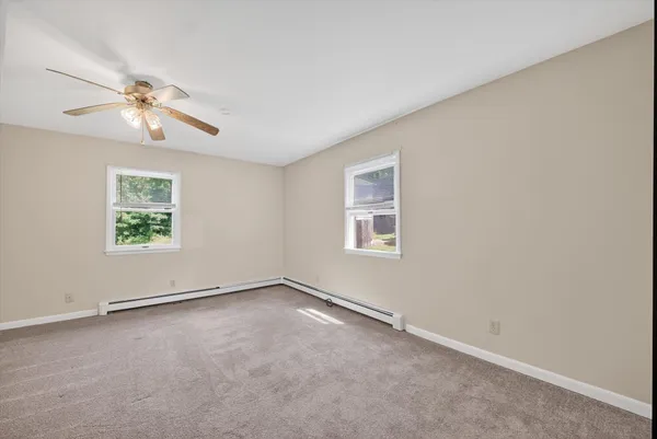 an empty room with windows and fan