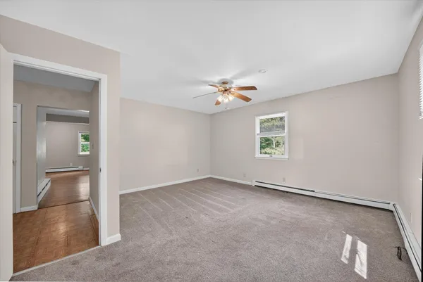 an empty room with windows and chandelier fan