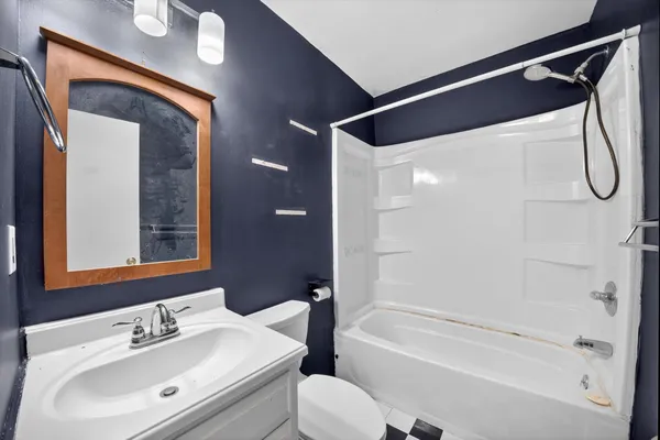 a bathroom with a bathtub shower sink vanity and toilet