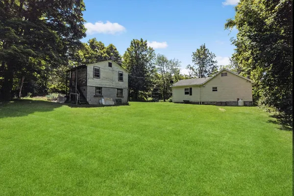 a house that is sitting in the grass with large trees