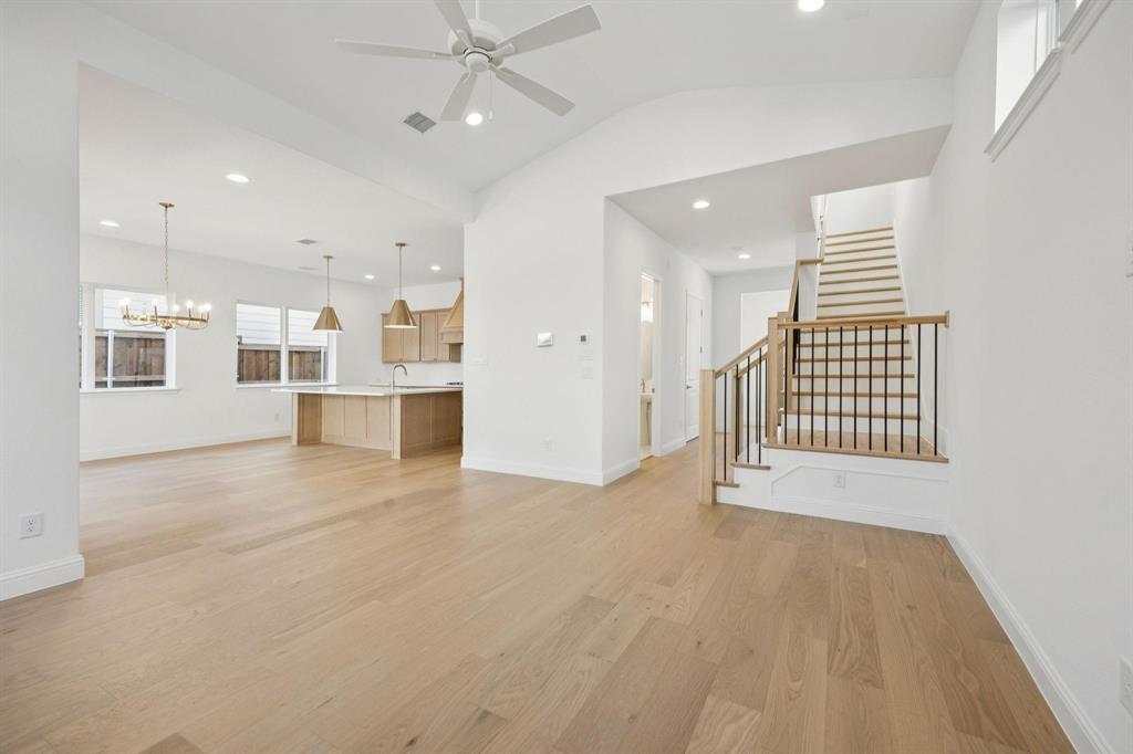 9620 Mav Lane Dallas, TX 75238 - Photo 4 of 11 Unfurnished living room featuring light wood finished floors, vaulted ceiling, a ceiling fan, and suspended lighting