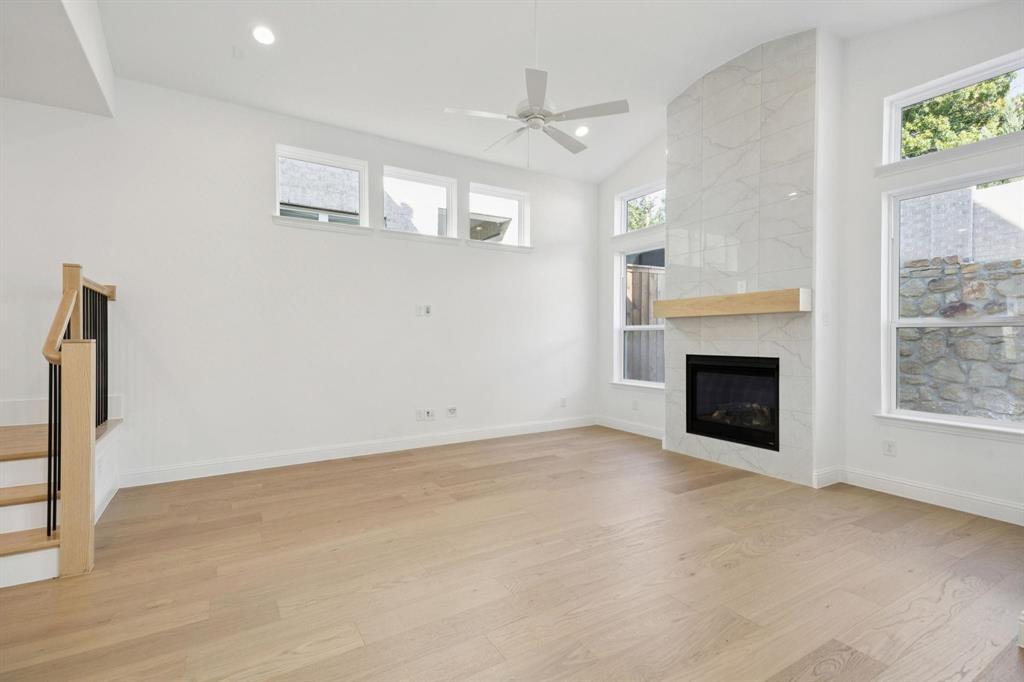 9620 Mav Lane Dallas, TX 75238 - Photo 5 of 11 Unfurnished living room with vaulted ceiling, light wood finished floors, a high end fireplace, a ceiling fan, and recessed lighting