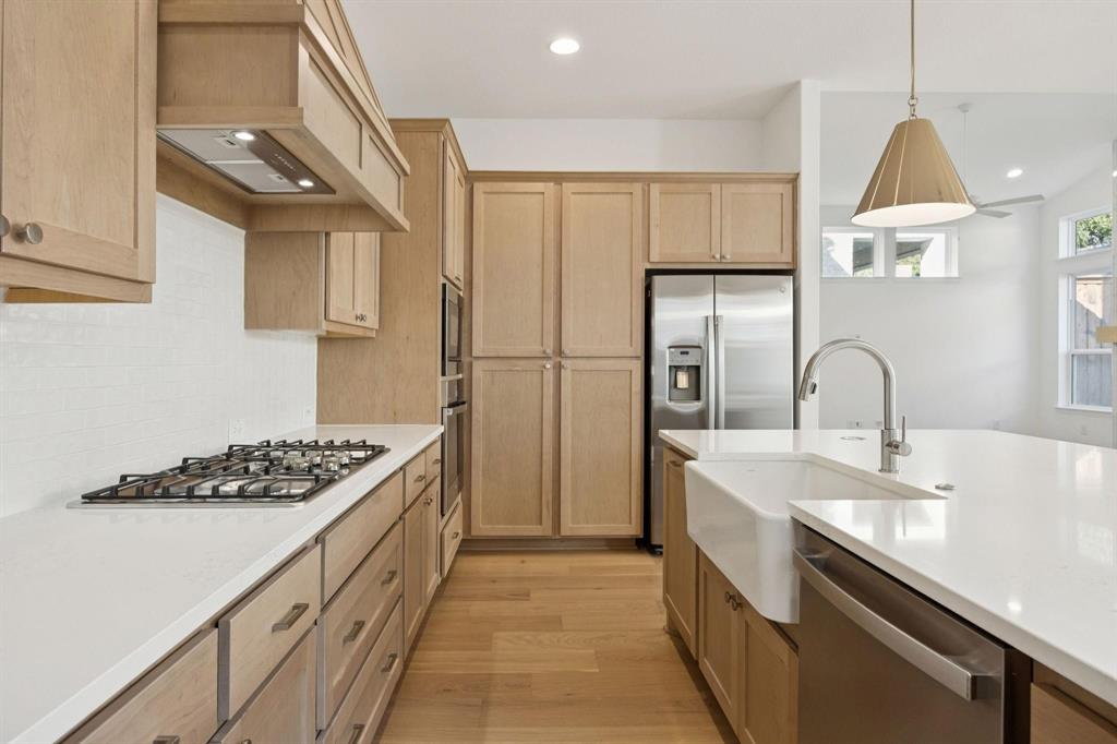 9620 Mav Lane Dallas, TX 75238 - Photo 6 of 11 Kitchen with light wood-style flooring, stainless steel appliances, hanging light fixtures, and light stone counters