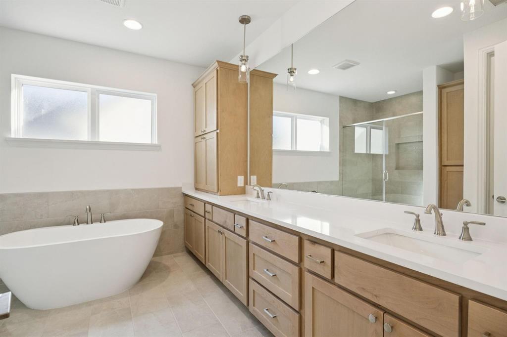 9620 Mav Lane Dallas, TX 75238 - Photo 9 of 11 Bathroom featuring a stall shower, double vanity, a freestanding bath, tile walls, and wainscoting
