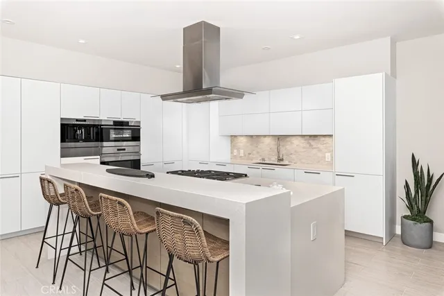 a kitchen with stainless steel appliances a sink a stove a microwave a dining table and chairs