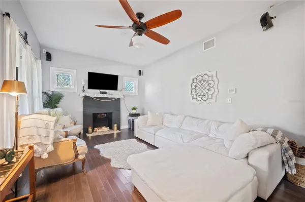 a living room with couches a flat screen tv and a stove with wooden floor