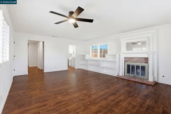 an empty room with wooden floor fireplace and windows