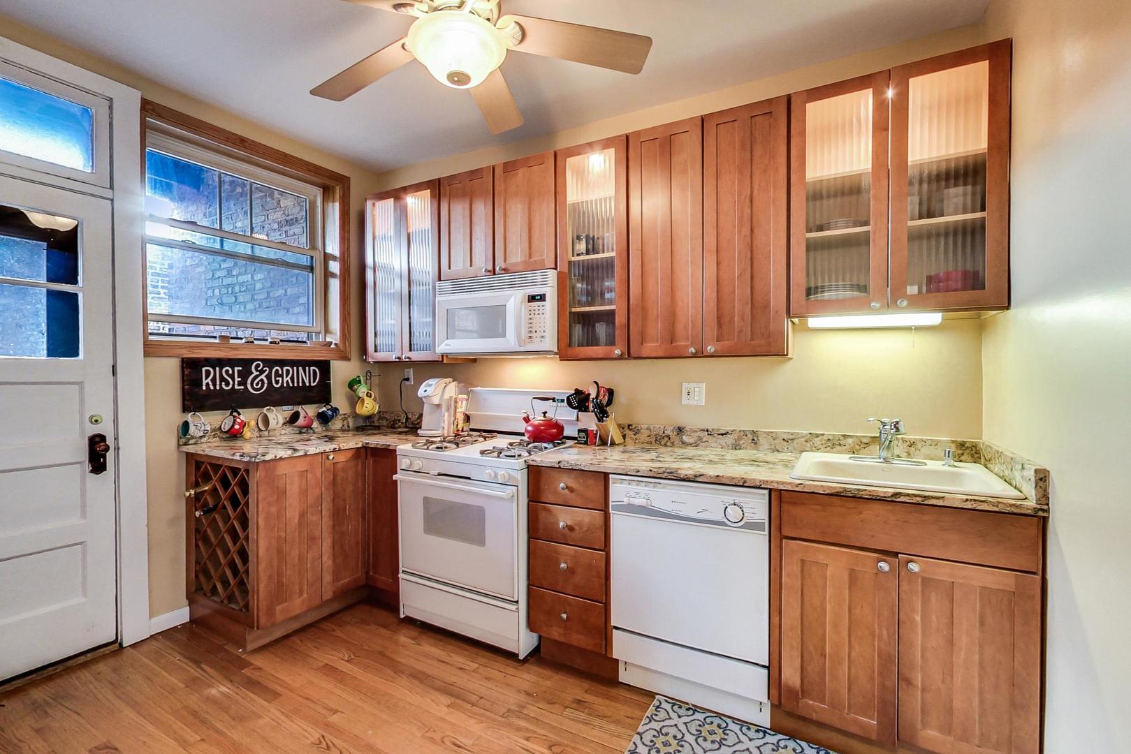 537 West Addison Street, Unit 3S Chicago, IL 60613 - Photo 7 of 19 a kitchen with stainless steel appliances granite countertop wooden cabinets a stove a sink and a large window