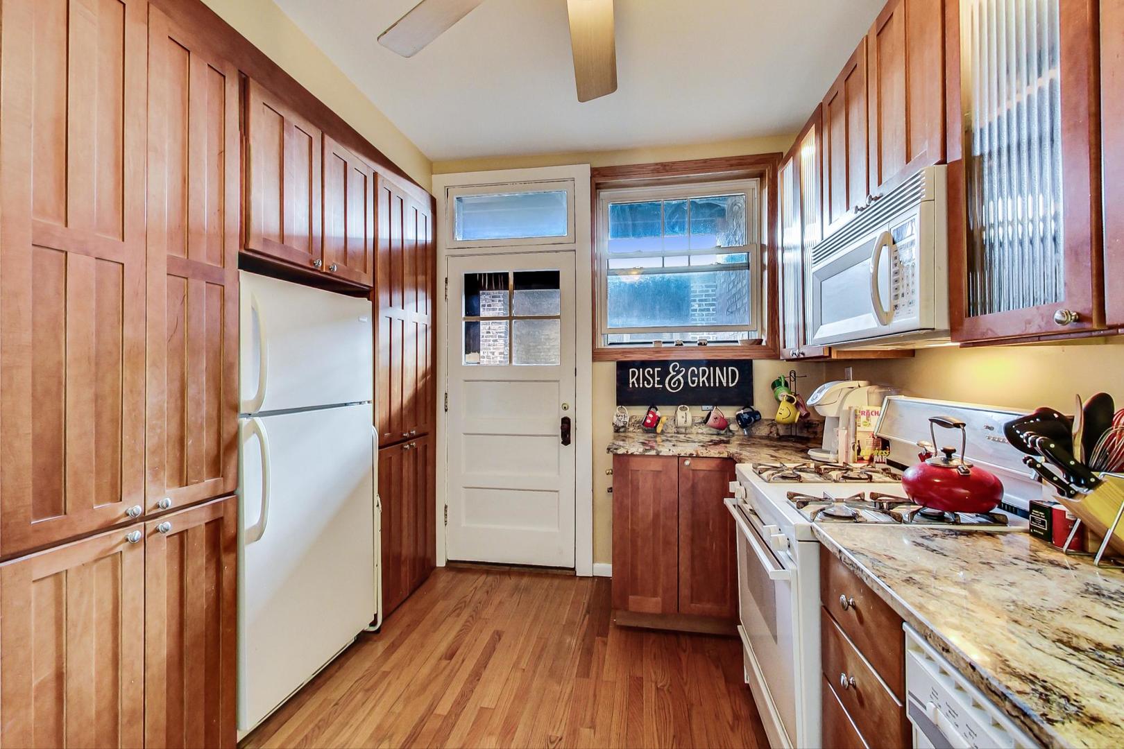 537 West Addison Street, Unit 3S Chicago, IL 60613 - Photo 8 of 19 a kitchen with stainless steel appliances granite countertop a refrigerator stove and wooden floor