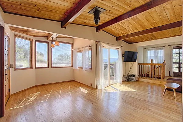 a view of an empty room with wooden floor and a window