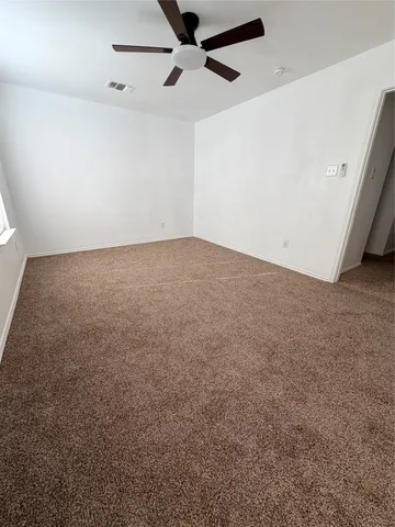 an empty room with a ceiling fan and a window
