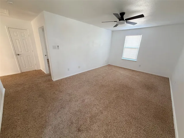 an empty room with a ceiling fan and windows